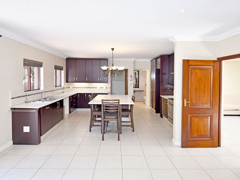 Spacious kitchen featuring dark wood cabinetry, stone countertops, a central island, and tiled flooring, offering a functional layout with ample storage space.