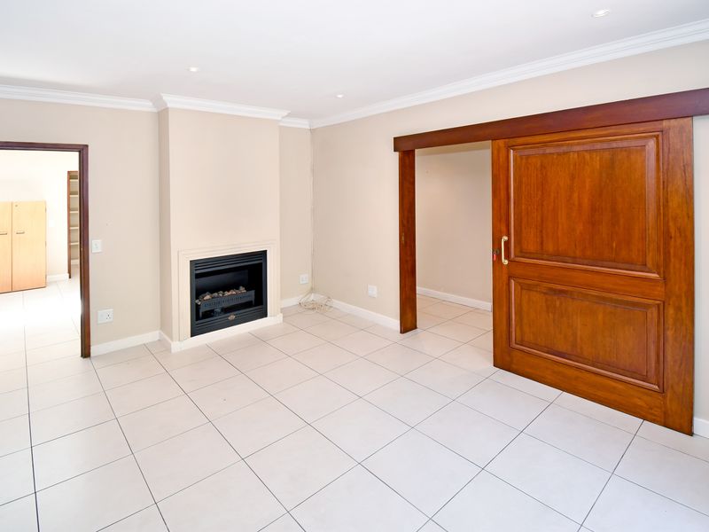 Spacious living area featuring neutral tiled flooring, a built-in fireplace, and a large wooden sliding door leading to an adjacent room.