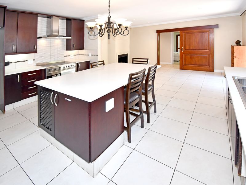 Spacious open-plan kitchen featuring a large central island with quartz countertops, stainless steel appliances, and a distinctive wooden sliding barn door.