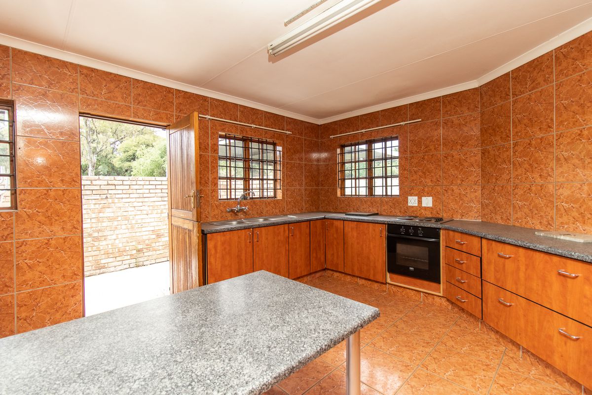 A functional kitchen featuring built-in wooden cabinetry, granite countertops, a built-in oven and hob, and direct access to an outdoor area.