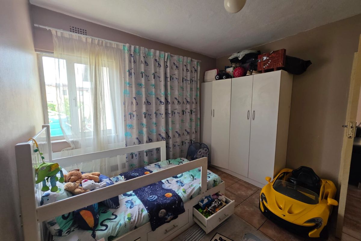A bedroom featuring tiled flooring and a built-in wardrobe, providing functional storage space within the room.