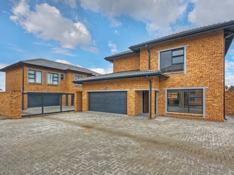 Modern double-storey townhouse featuring a face brick exterior, tiled roof, paved driveway, and a secure double garage with an automated door.