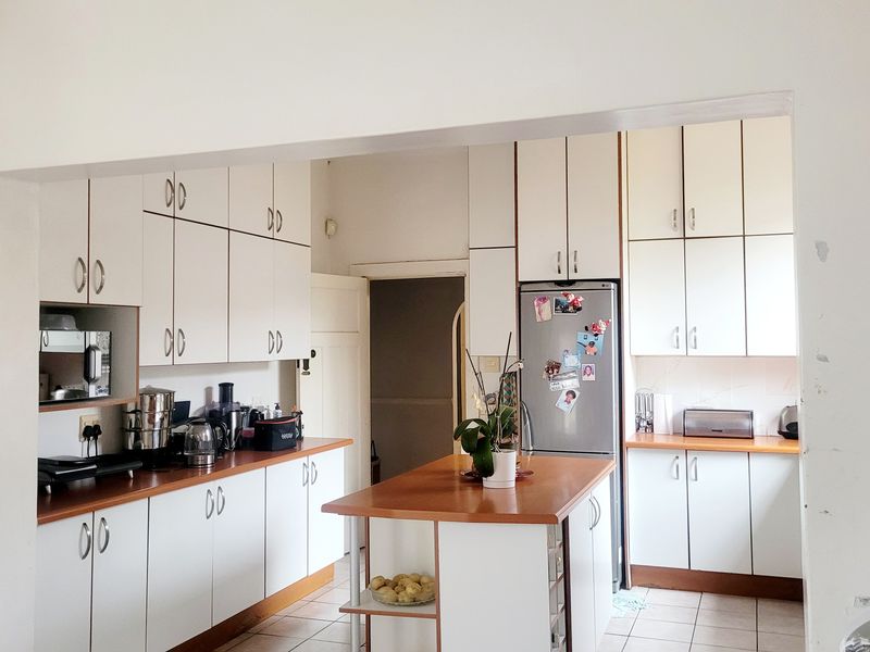 A functional kitchen featuring white cabinetry, laminate countertops, a central island, and tiled flooring, offering a practical layout for daily use.