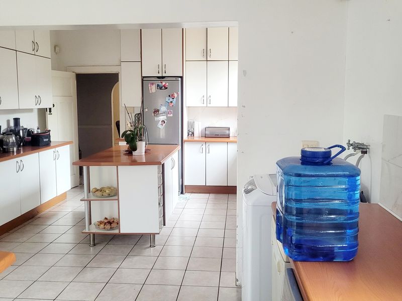 A functional kitchen featuring white cabinetry, laminate countertops, a central island, and tiled flooring, offering a practical layout for daily use.