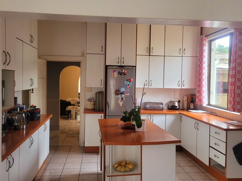 A functional kitchen featuring white cabinetry, a central island, tiled flooring, and ample counter space, offering potential for modern updates.
