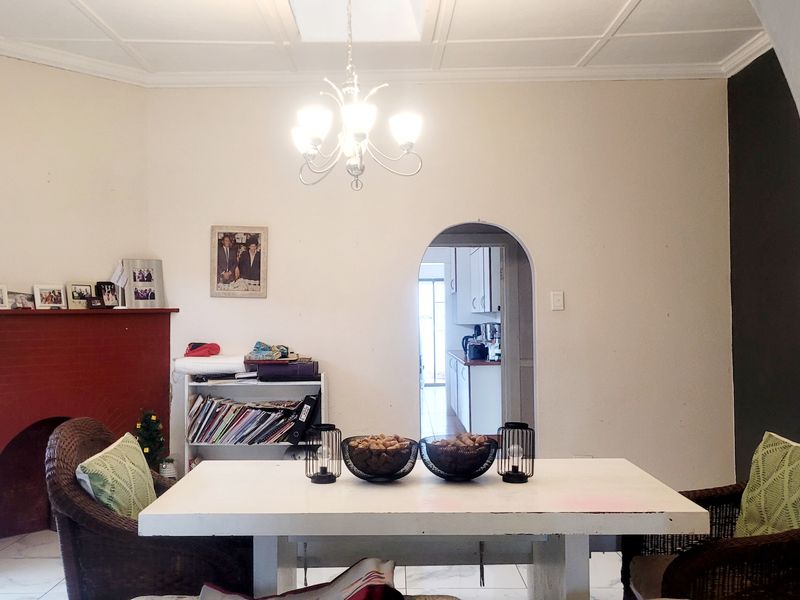 Dining room featuring a brick fireplace, coffered ceiling, and an arched doorway leading to the kitchen area.
