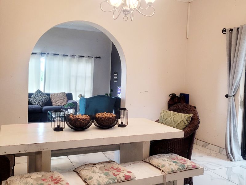 Dining area featuring an arched transition to the living space, tiled flooring, and bi-fold doors providing access to the exterior.