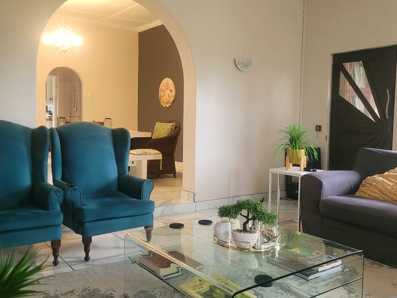 A living room featuring an arched doorway leading to an adjacent space, tiled flooring, and wall-mounted lighting fixtures.