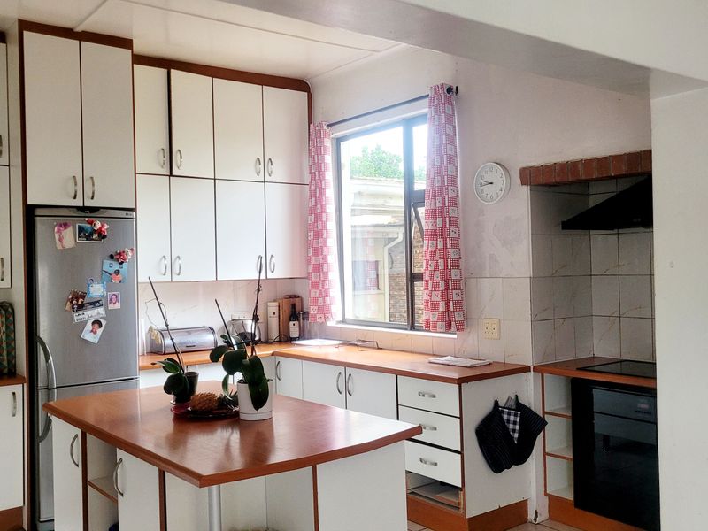 A functional kitchen featuring white cabinetry, wood-look countertops, a central island, and built-in cooking appliances, offering a practical layout with potential for modernization.