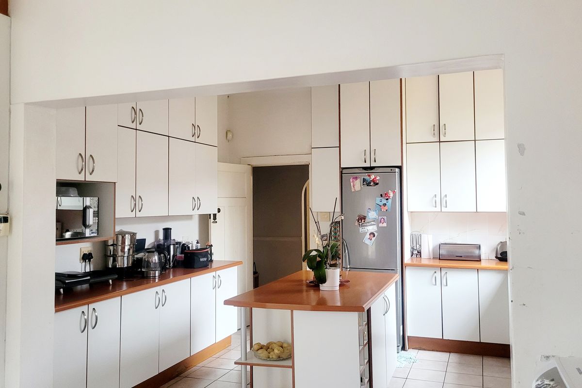 A functional kitchen featuring white cabinetry, laminate countertops, a central island, and tiled flooring, offering a practical layout for daily use.