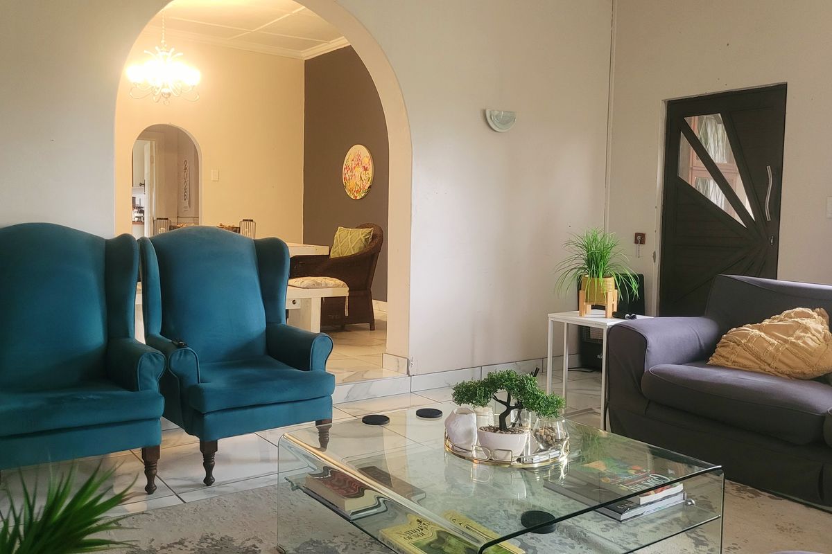 A living room featuring an arched doorway leading to an adjacent space, tiled flooring, and wall-mounted lighting fixtures.