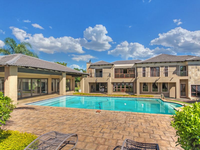 Spacious rear exterior featuring a large swimming pool, expansive paved patio area, and a covered outdoor entertainment space attached to the main residence.