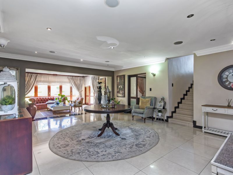 Spacious open-plan living area featuring polished tile flooring, recessed lighting, and a central staircase leading to the upper level.