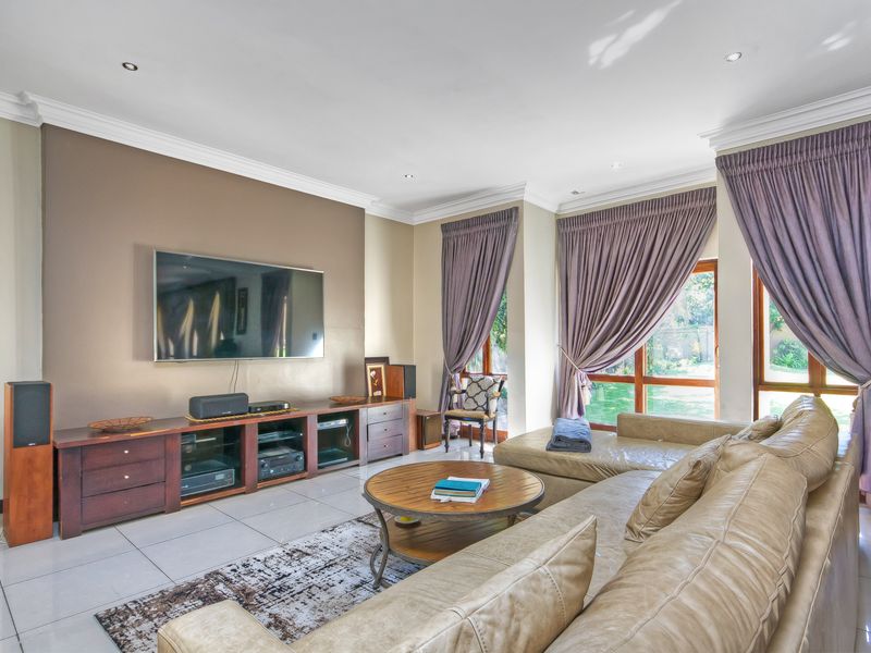Spacious living room featuring tiled flooring, recessed downlighting, crown molding, and large glass sliding doors providing natural light and garden access.