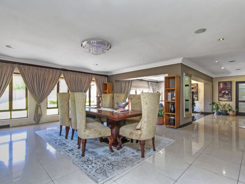 Spacious dining room featuring polished porcelain floor tiles, recessed downlighting, a decorative crystal chandelier, and large windows with integrated curtain tracks.