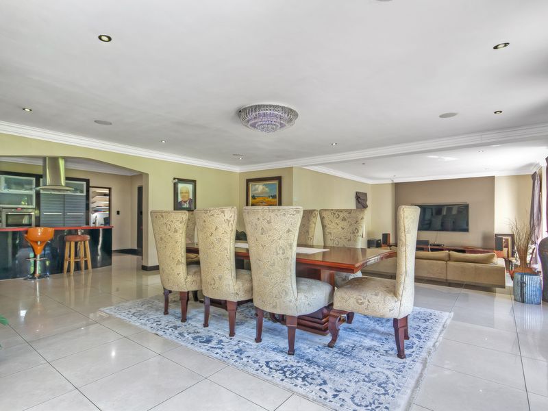 Spacious open-plan living and dining area featuring polished porcelain tiles, recessed lighting, and a modern kitchen with a breakfast bar and extractor fan.