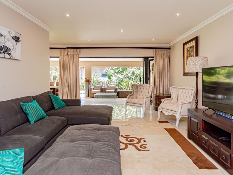 Spacious living room featuring polished tile flooring, recessed downlighting, and large sliding glass doors that open to an outdoor patio area.