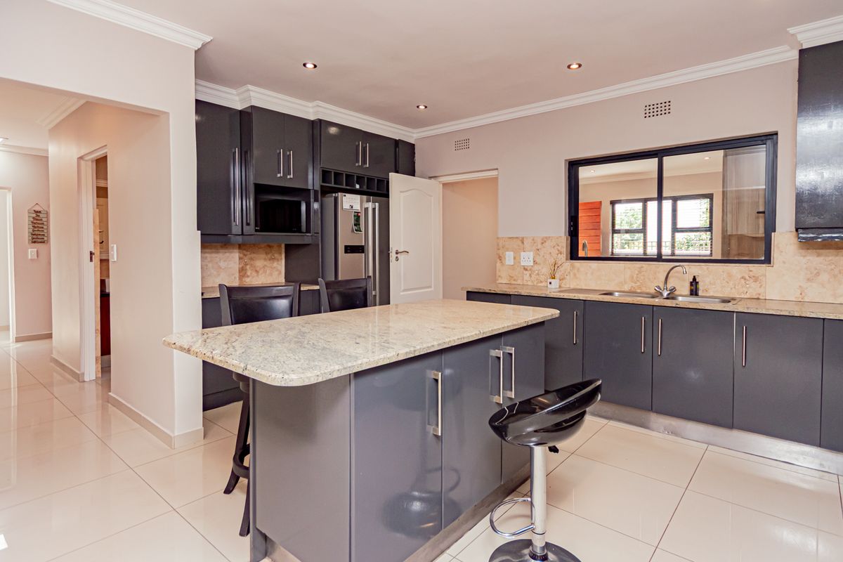 Modern kitchen featuring dark cabinetry, granite countertops, a central island, and tiled flooring, offering a functional and contemporary cooking space.
