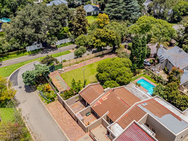 Aerial view of the property showcasing the residential layout, swimming pool, garden area, and surrounding neighborhood landscape.