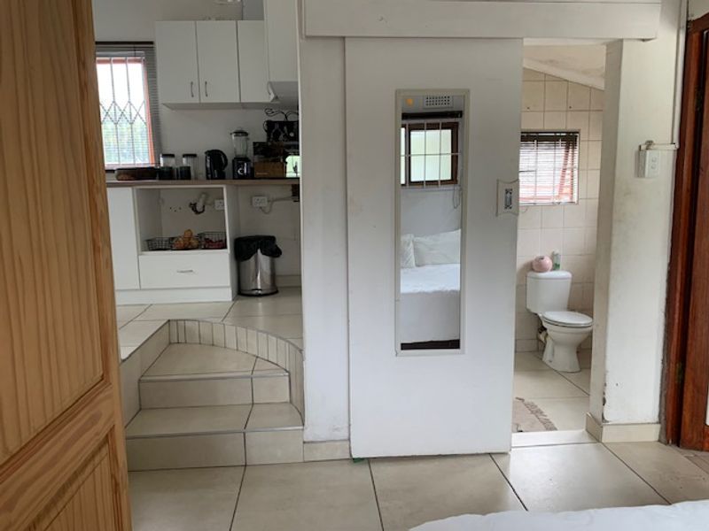 Open plan living area featuring tiled flooring, built-in kitchen cabinetry, and direct access to an adjoining bathroom through a sliding door.