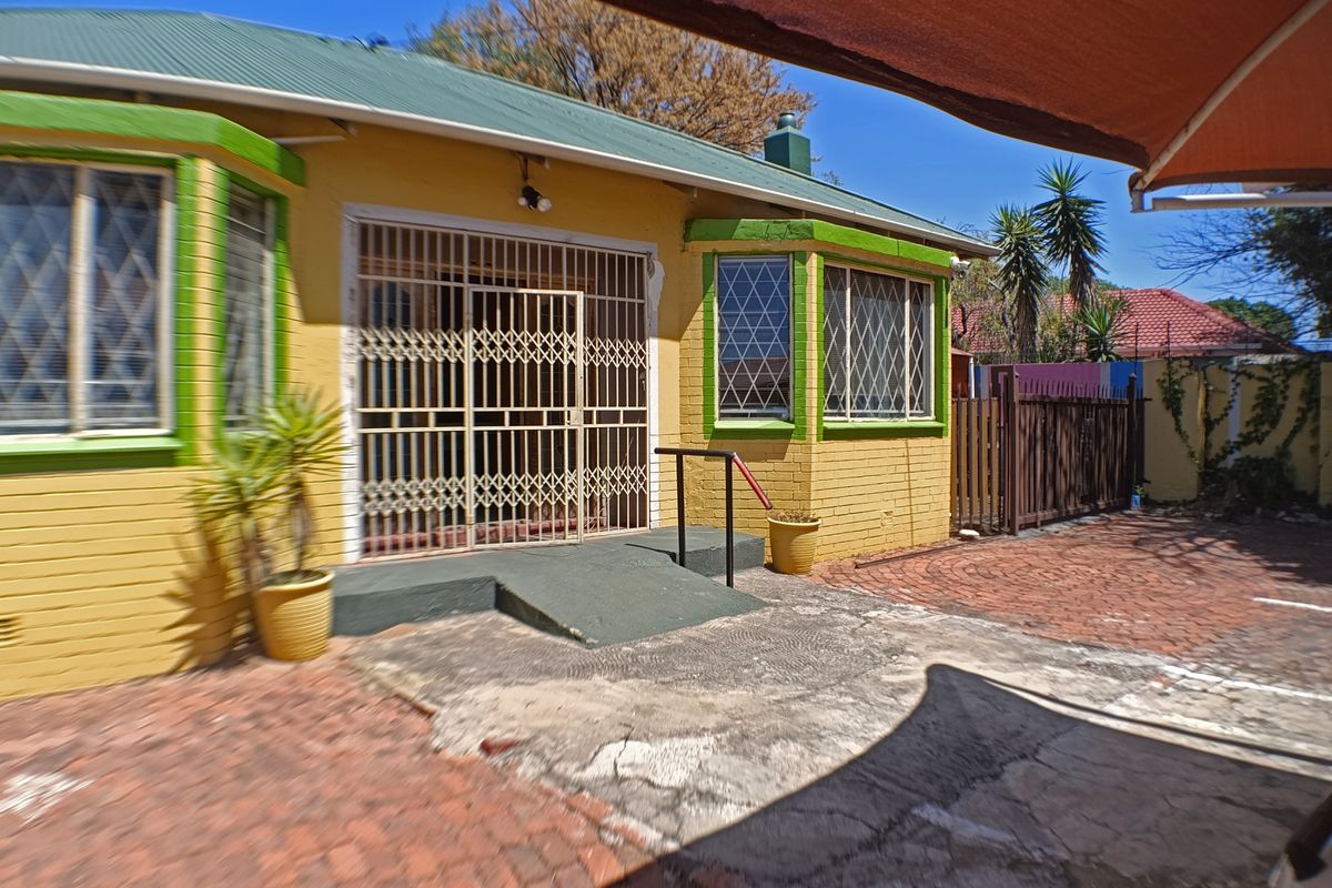 Rear exterior view of the property featuring a brick paved courtyard, concrete ramp access, and security gates on the building entrance.