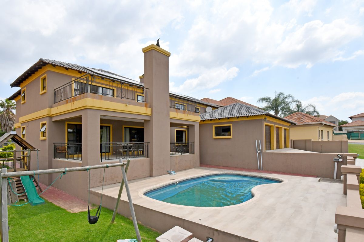 Rear view of a two-story house featuring a swimming pool, tiled patio area, upper-level balconies, and a prominent chimney stack.