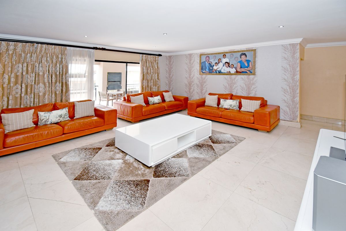 Spacious living room featuring large format floor tiles, recessed downlighting, and sliding glass doors leading to an outdoor patio area.