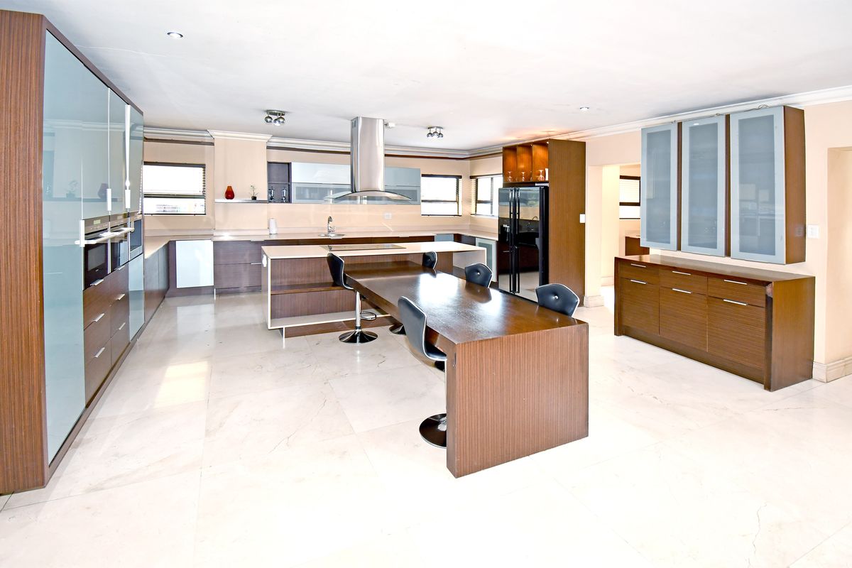 Spacious modern kitchen featuring extensive built-in cabinetry, a large central island with integrated seating, stone countertops, and high-quality built-in appliances.