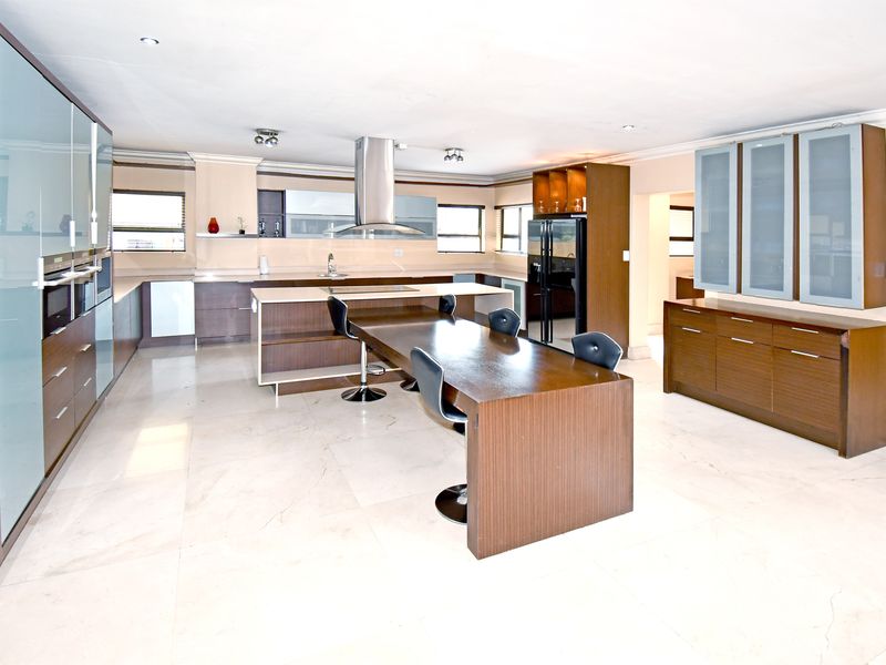 Spacious modern kitchen featuring extensive built-in cabinetry, a large central island with integrated seating, stone countertops, and high-quality built-in appliances.