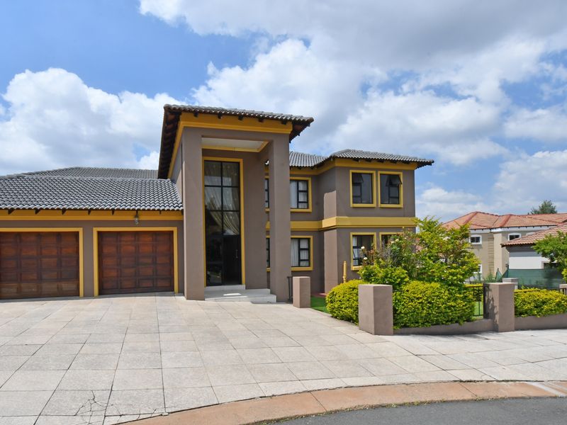 A well-maintained double-story residential property featuring a double garage, paved driveway, and a prominent double-volume entrance facade.