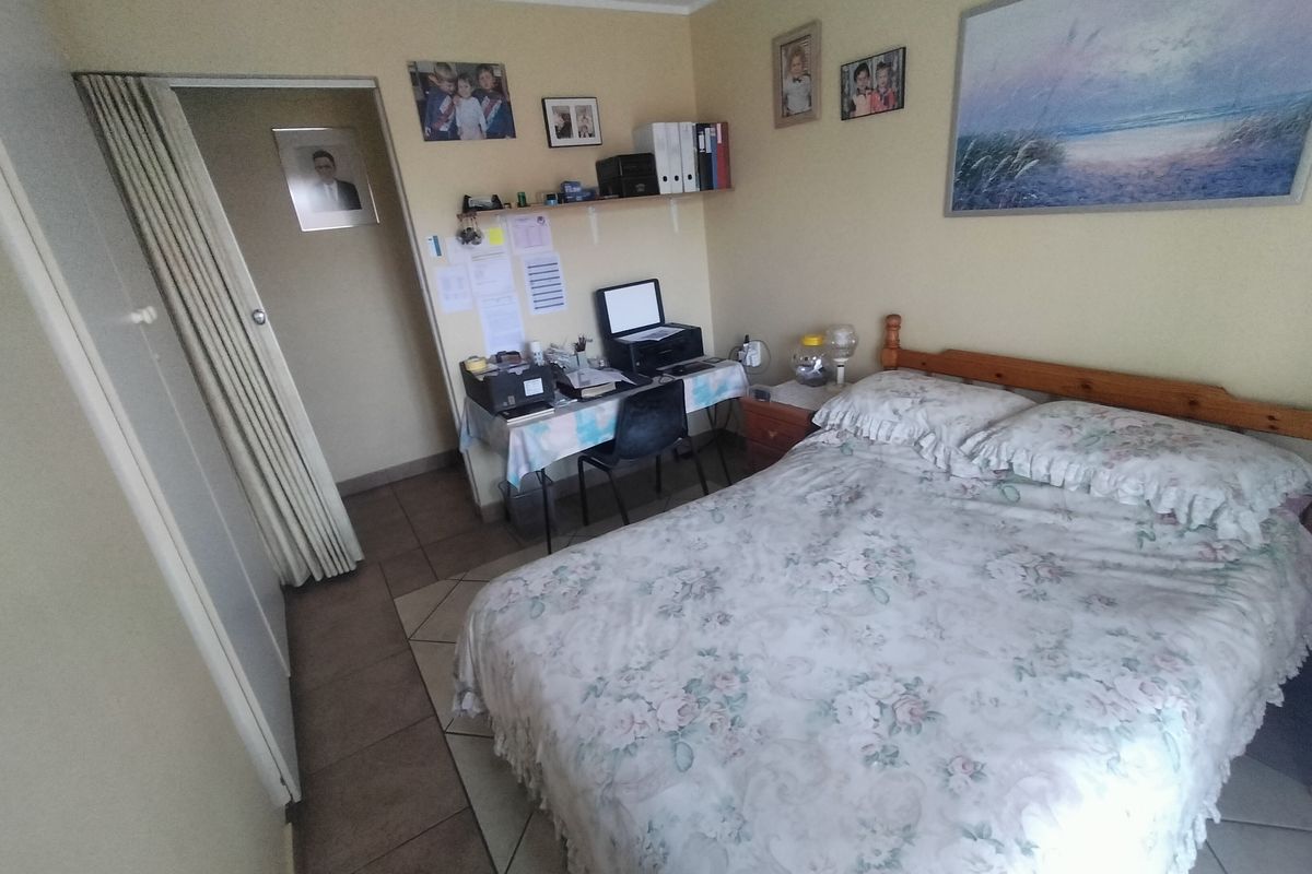 A functional bedroom featuring tiled flooring, a built-in wardrobe, and a folding door, offering a practical layout for a retirement village residence.