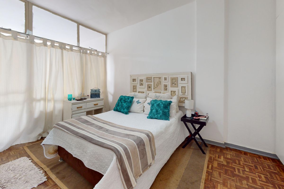 A bright bedroom featuring classic parquet flooring, a built-in wardrobe, and large clerestory windows that allow for ample natural light.
