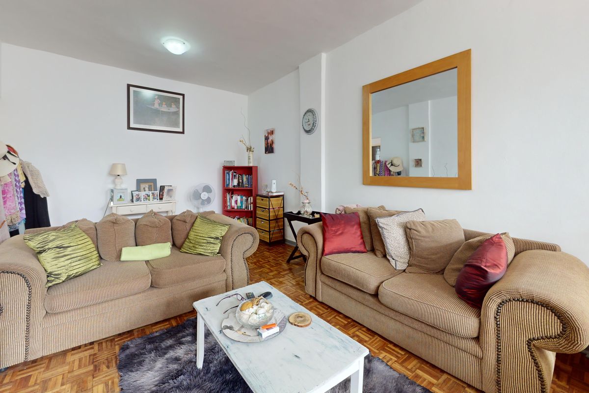 A comfortable living room featuring classic parquet flooring and neutral wall finishes, providing a versatile space for relaxation.