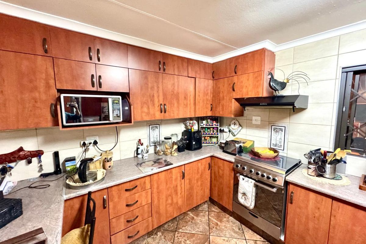A functional kitchen featuring wood-look cabinetry, laminate countertops, a built-in oven with extractor fan, and tiled flooring.