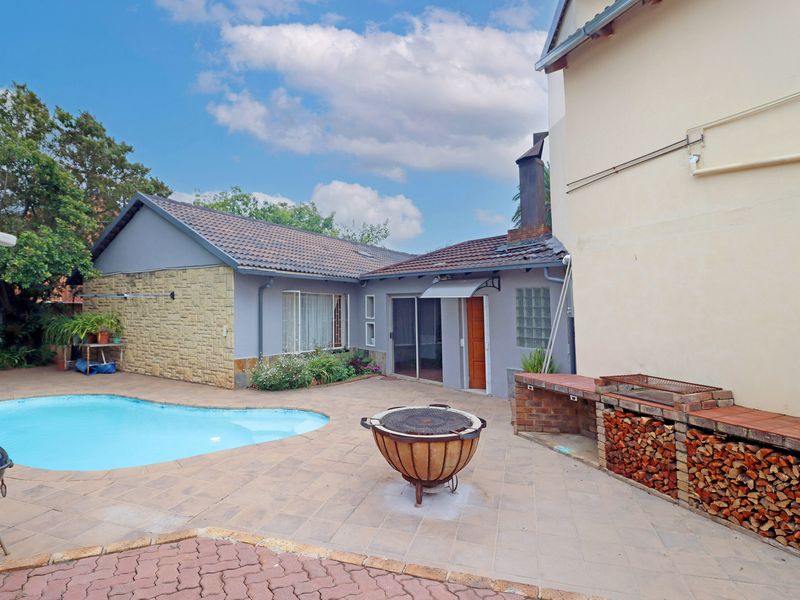 Outdoor entertainment area featuring a swimming pool, paved patio, and a built-in brick braai facility.