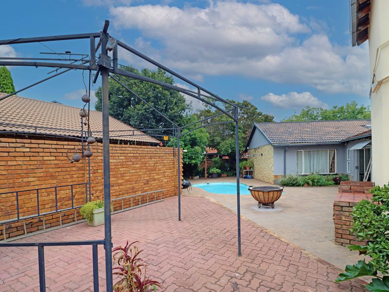 Rear outdoor area featuring a paved patio, swimming pool, and brick boundary wall, providing a functional space for outdoor living and entertainment.