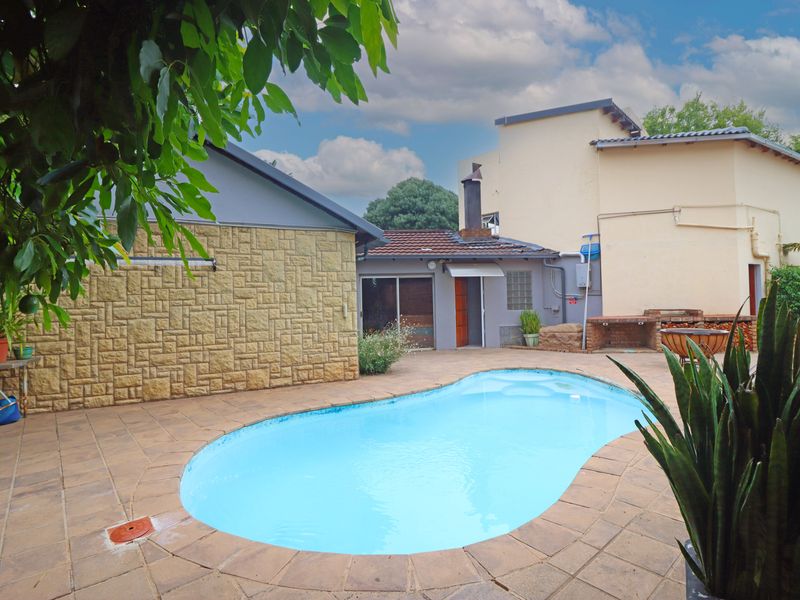 Outdoor pool area featuring a swimming pool, paved surround, and a built-in brick braai area against the rear building facade.