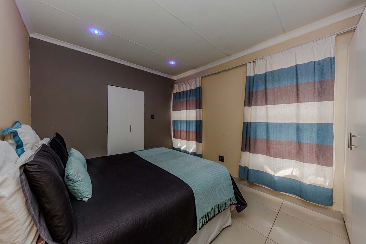 A bedroom featuring tiled flooring, built-in cupboards, and recessed downlighting.
