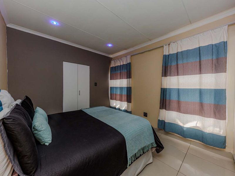 A bedroom featuring tiled flooring, built-in cupboards, and recessed downlighting.