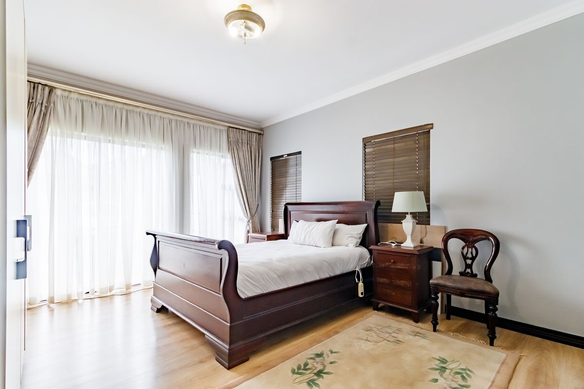 Spacious bedroom featuring laminate flooring, built-in cupboards, and large sliding glass doors that provide ample natural light.