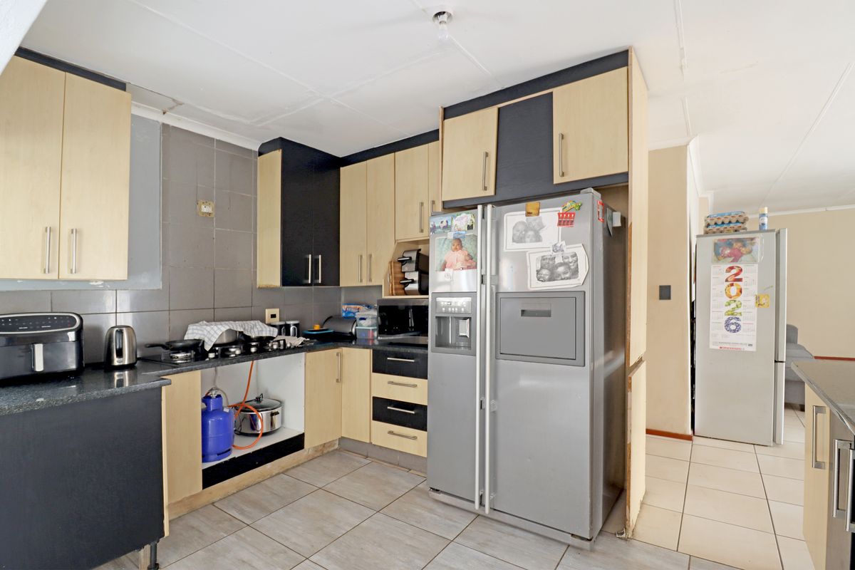 A functional kitchen featuring laminate cabinetry, granite countertops, and tiled flooring, currently requiring minor repairs and cosmetic updates to improve its overall finish.