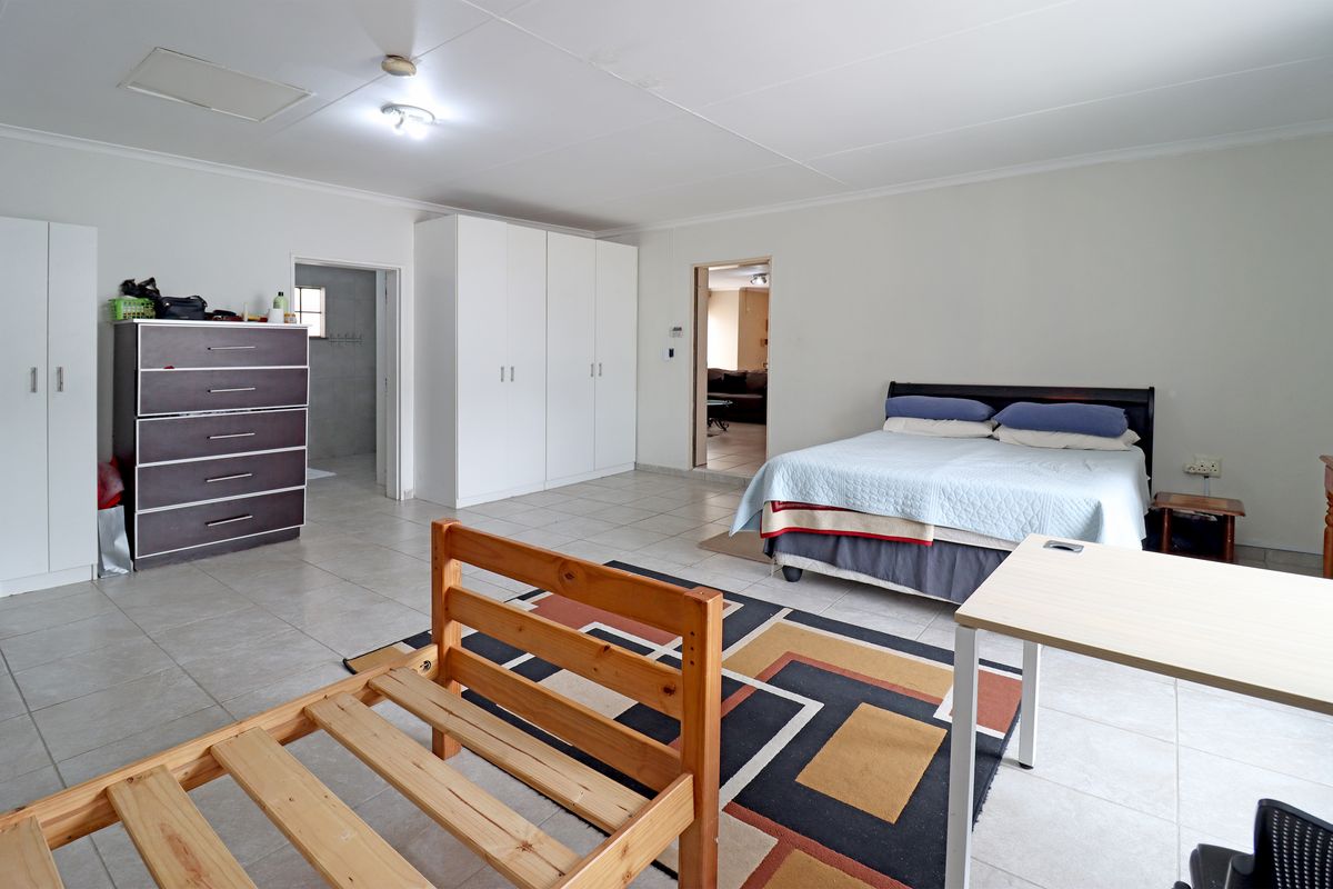 Spacious bedroom featuring neutral tiled flooring, ample built-in cupboard storage, and direct access to an adjoining room.
