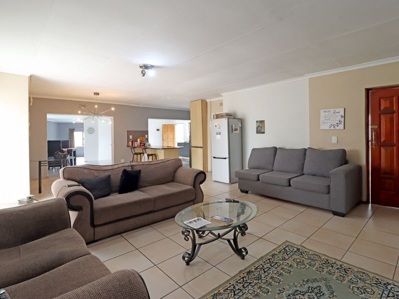 Spacious open-plan living area featuring tiled flooring, a central kitchen island, and direct access to the main entrance.
