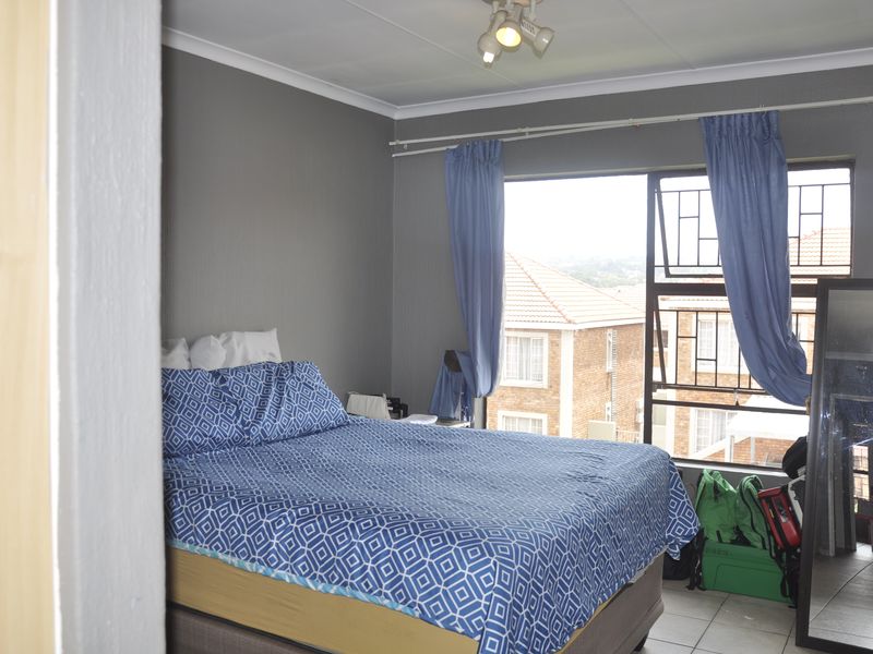 A bedroom featuring tiled flooring, security bars on the window, and a ceiling-mounted spotlight fixture.