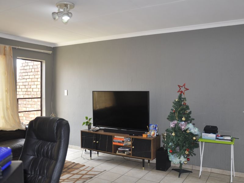 A living room featuring grey textured walls, tiled flooring, and a ceiling-mounted spotlight fixture.