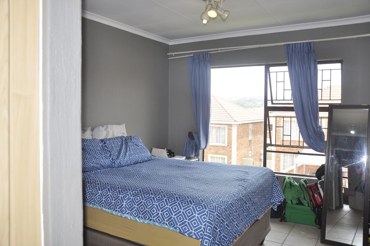 A bedroom featuring tiled flooring, security bars on the window, and a ceiling-mounted spotlight fixture.