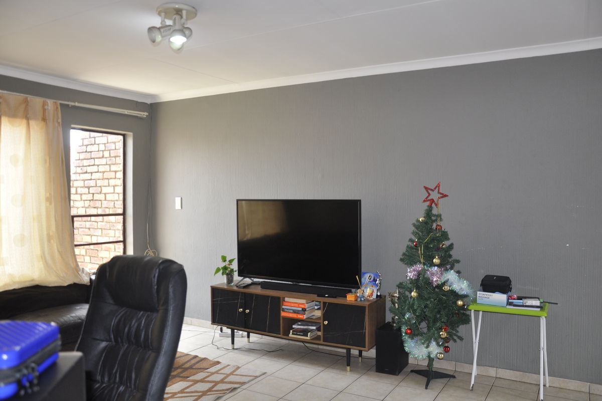 A living room featuring grey textured walls, tiled flooring, and a ceiling-mounted spotlight fixture.