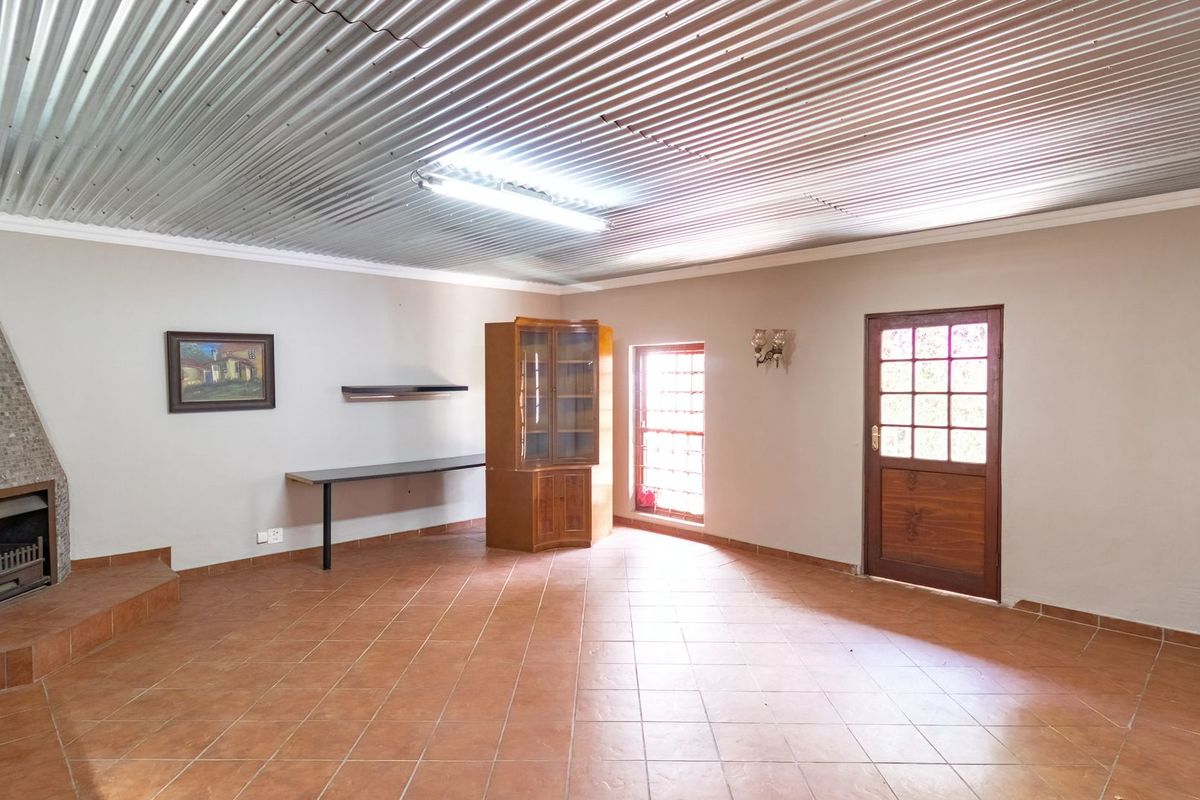 Spacious living area featuring a unique corrugated metal ceiling, tiled flooring, and a built-in fireplace with a tiled hearth.