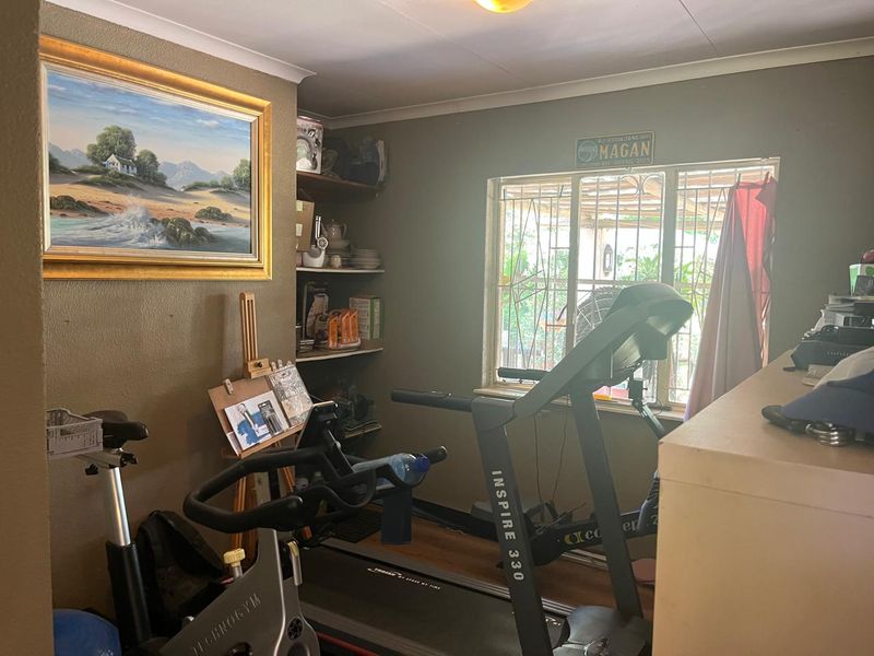 A functional home gym space featuring built-in shelving and a window with security bars, providing a dedicated area for fitness activities.