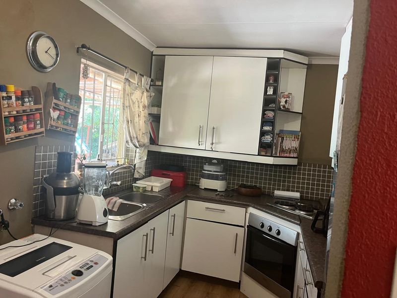 A functional kitchen featuring white cabinetry, dark laminate countertops, a tiled backsplash, and integrated cooking appliances.